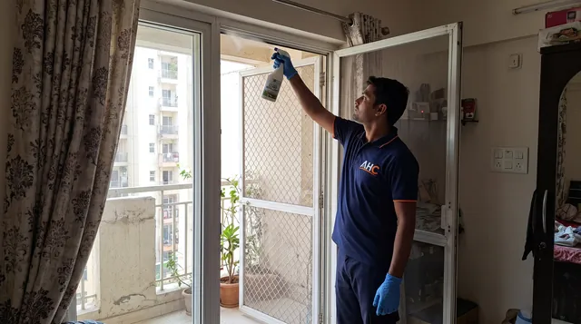 AHC technician spraying lizard repellent along a balcony door frame
